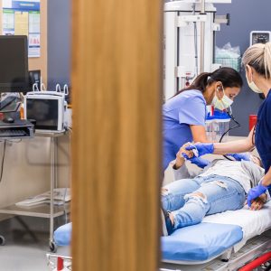 Medical staff bent over a prone patient in a hospital bed