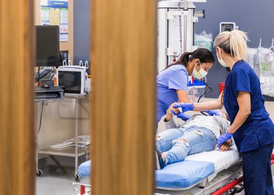 Medical staff bent over a prone patient in a hospital bed
